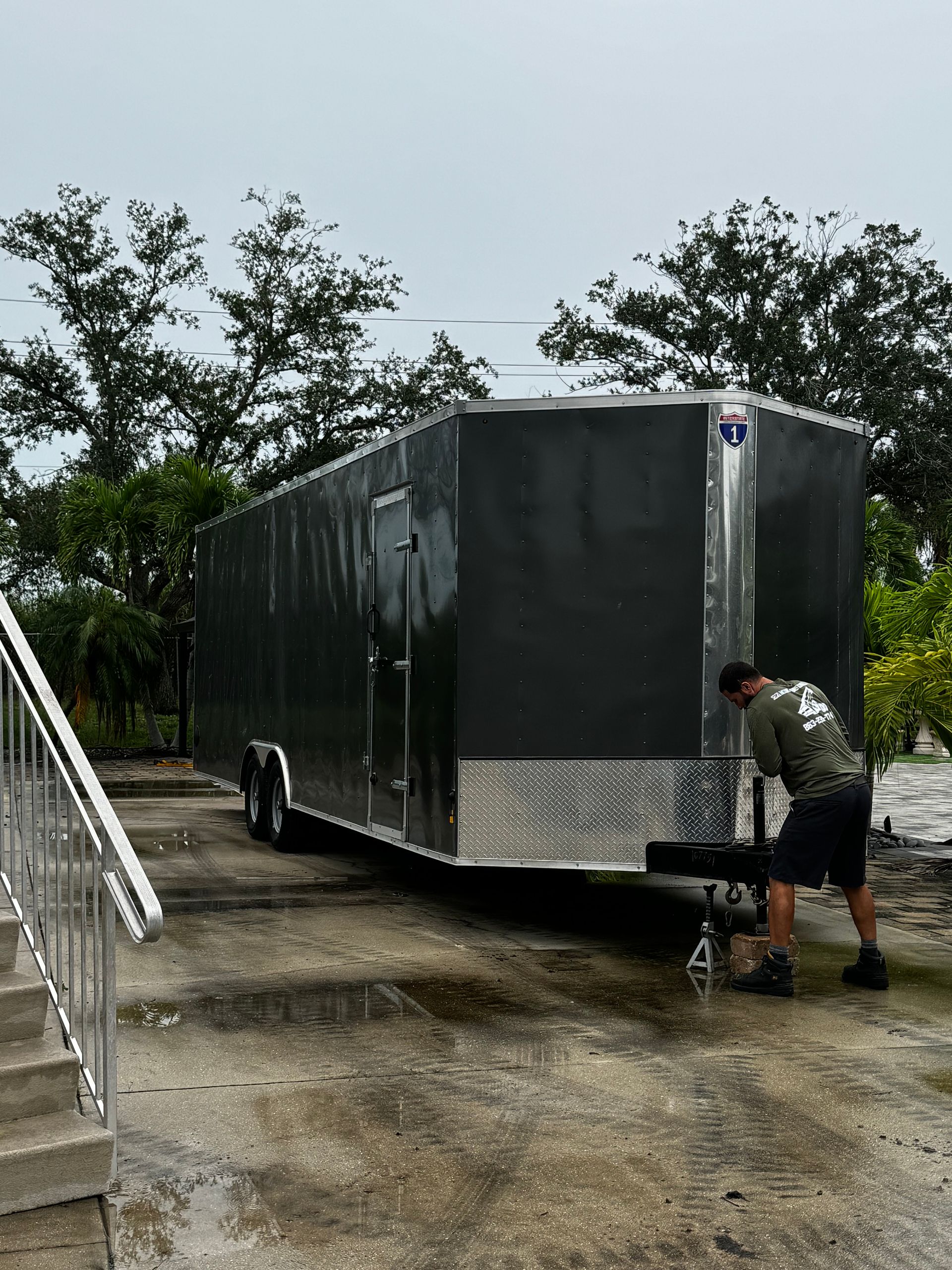 A man is standing next to a trailer in a parking lot.