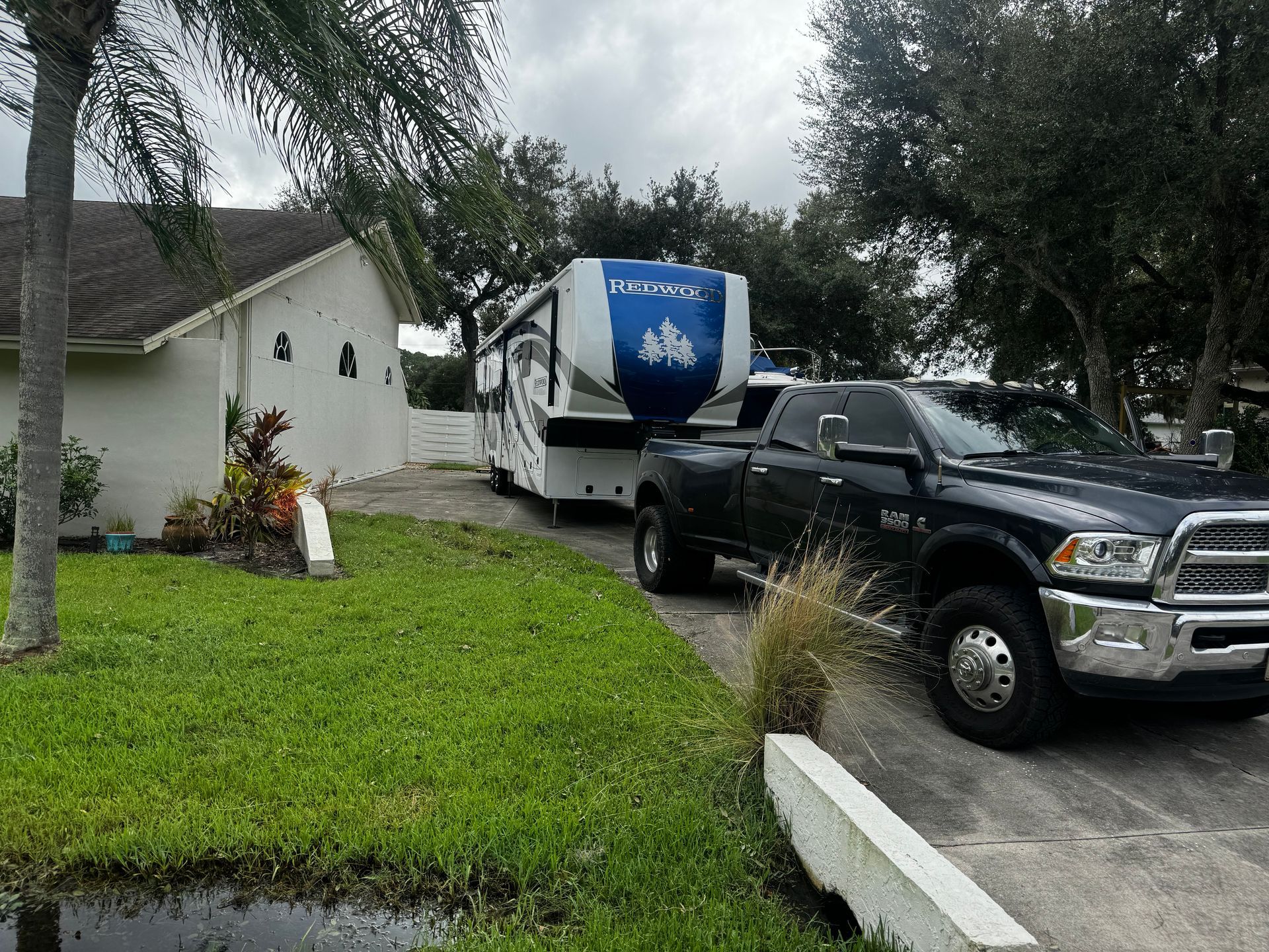 A truck is parked in front of a house with a trailer attached to it.
