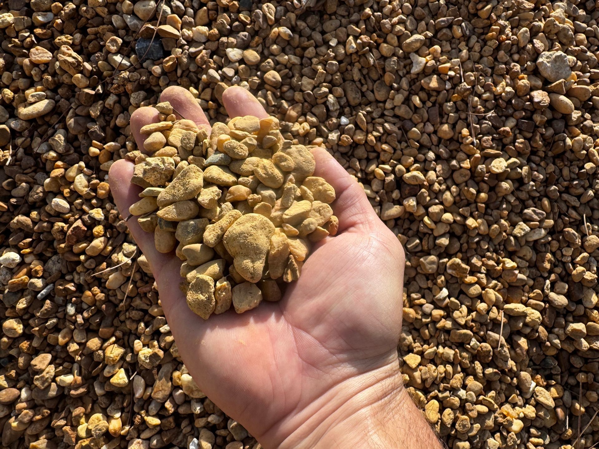 A person is holding a pile of gravel in their hand.