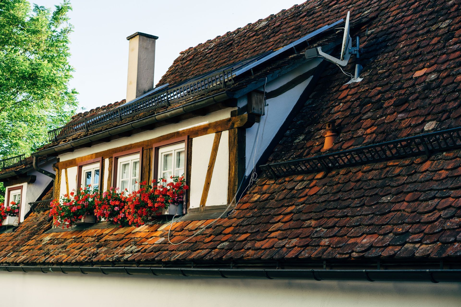 Red-roofed house with flower boxes and white-framed windows under a blue sky