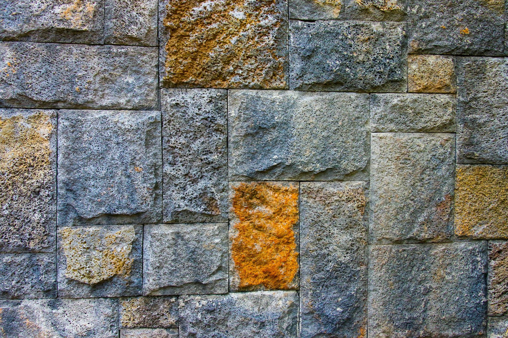Stone wall with gray and blue blocks, including a few orange-tinted stones.