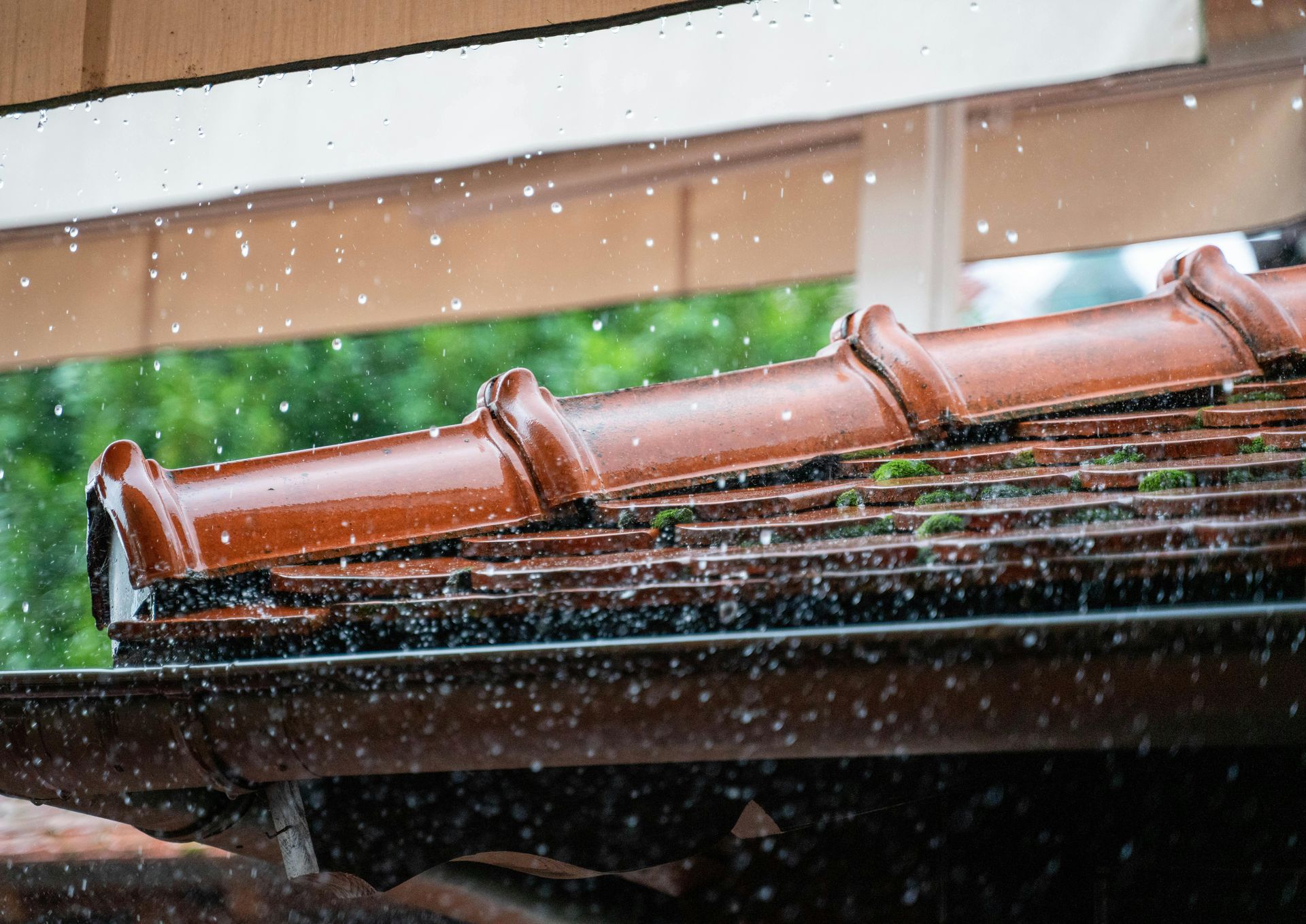 Rain falling on a red-tiled roof under a window frame
