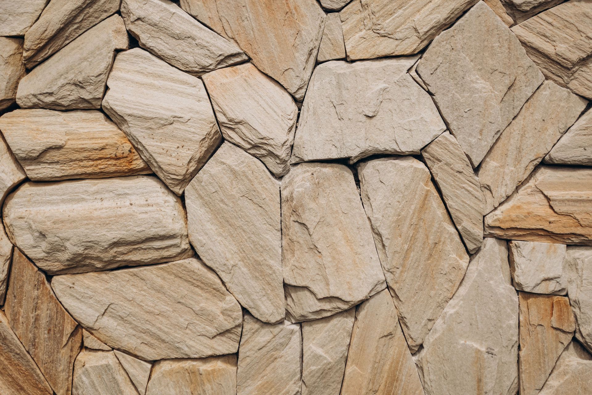 Close-up of a beige stone wall made of irregular stacked rocks