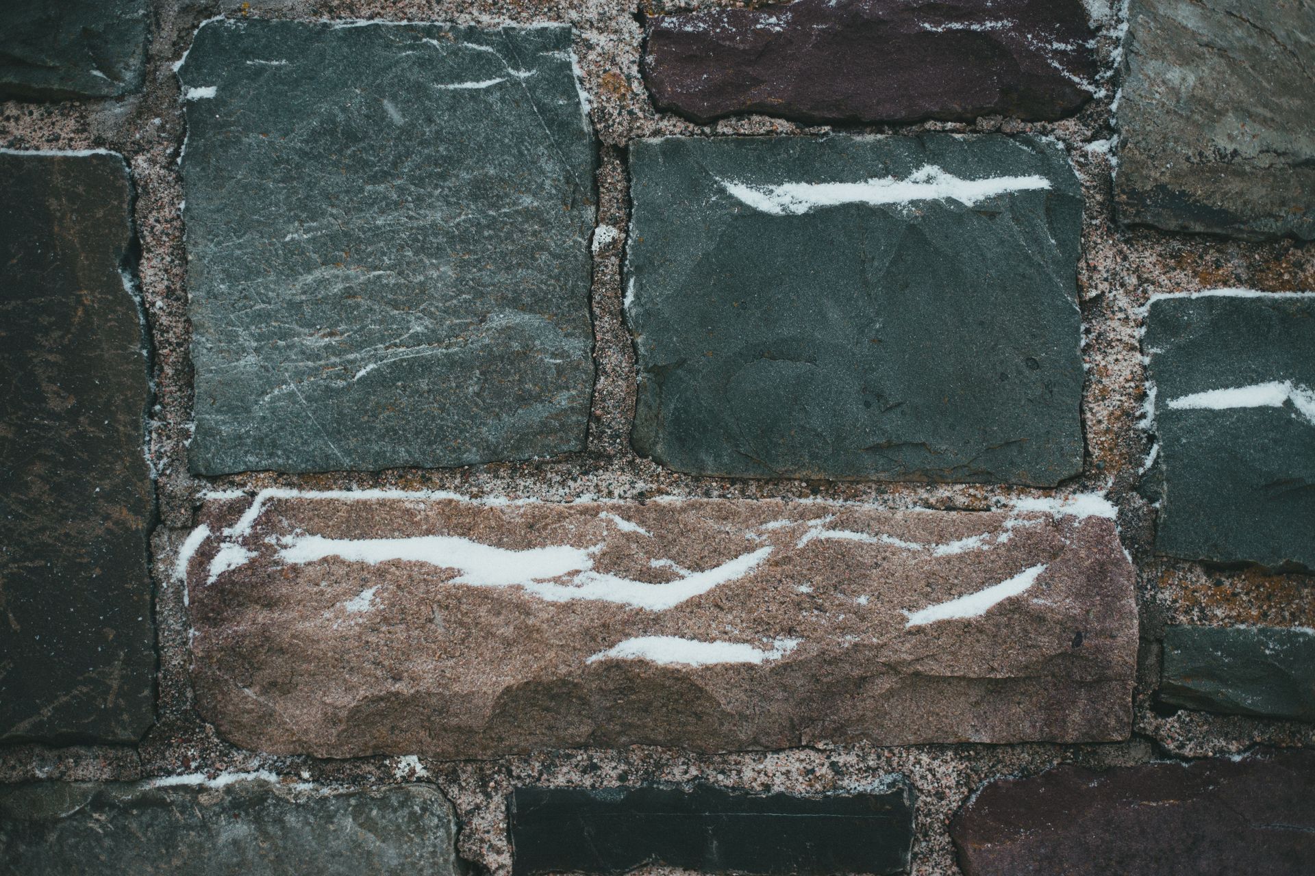 Rough stone wall with dark green and brown blocks and white mortar lines