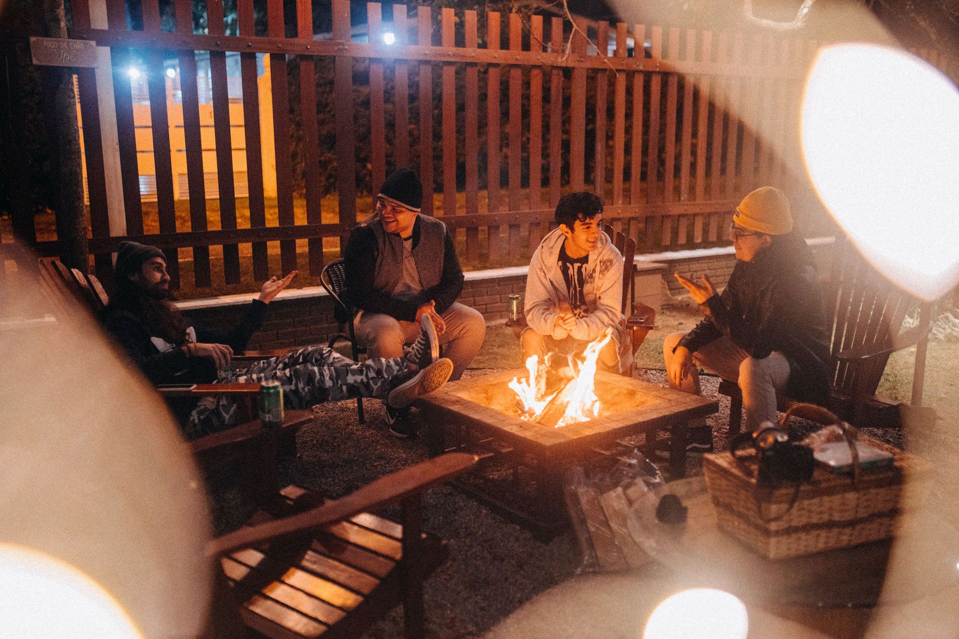 People gathered around a small fire pit on a patio at night.