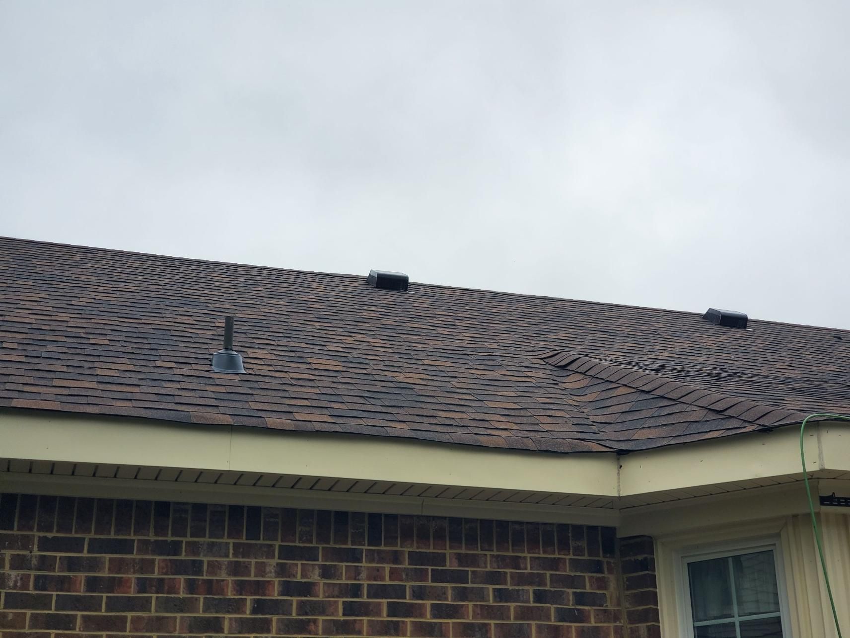 Roofer using a nail gun to install asphalt shingles on a roof.
