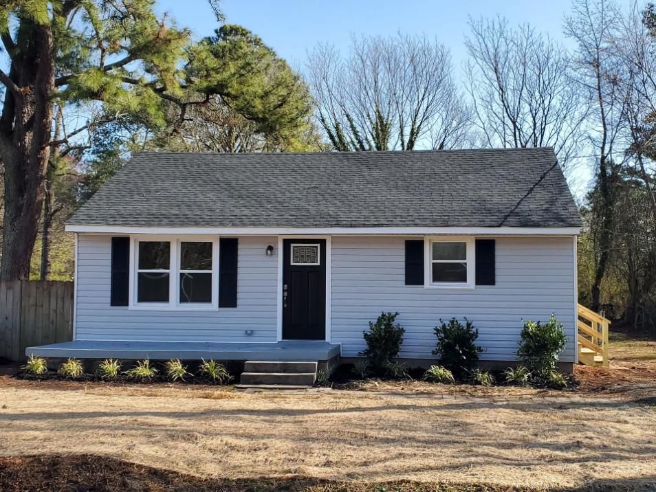 Light blue house with black shutters, door, and a gray roof.