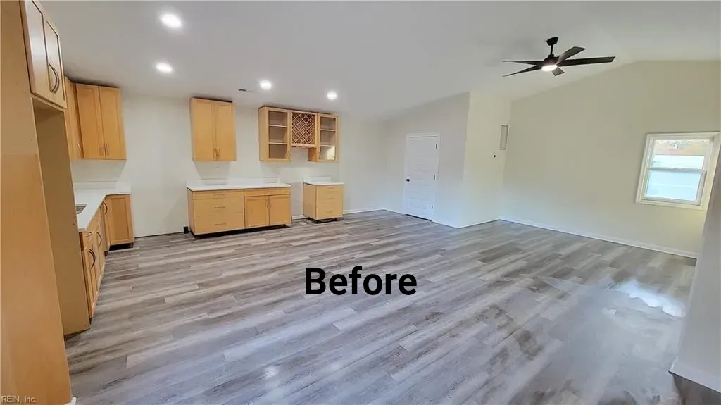 Interior view of a kitchen before renovation, featuring light wood cabinets and gray wood-look flooring.