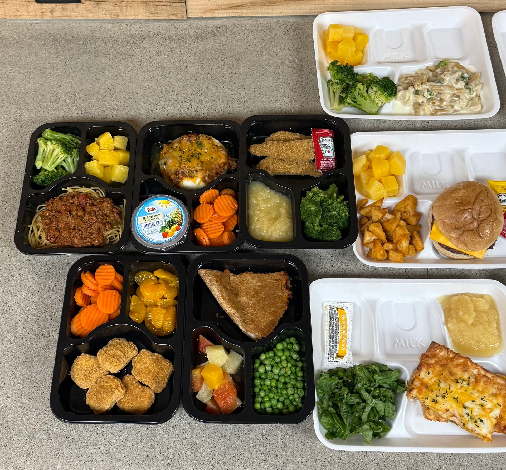 A bunch of trays of food are sitting on a table.