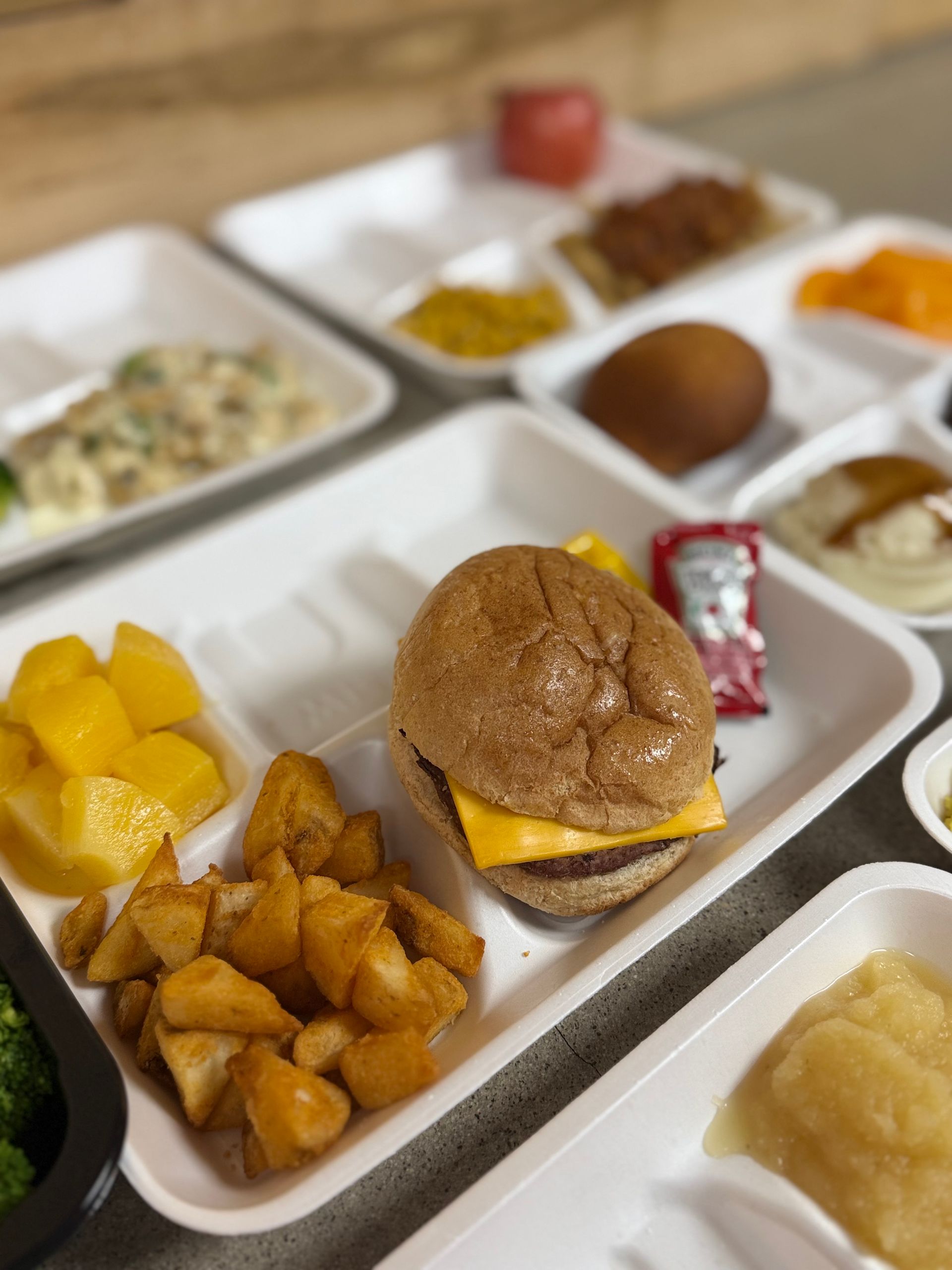 A tray of food with a hamburger and potatoes on it