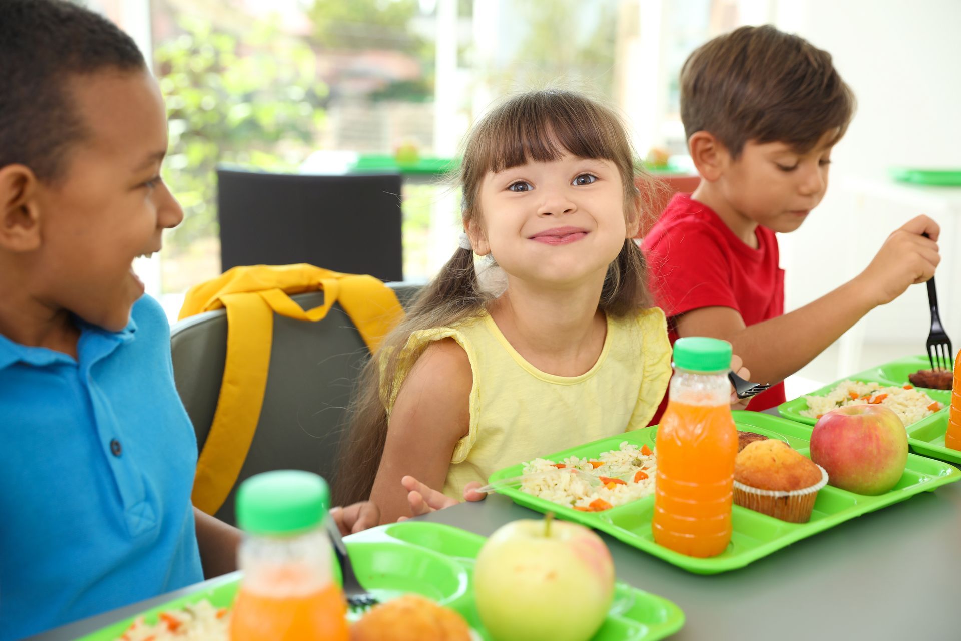 A group of children are sitting at a table eating lunch.