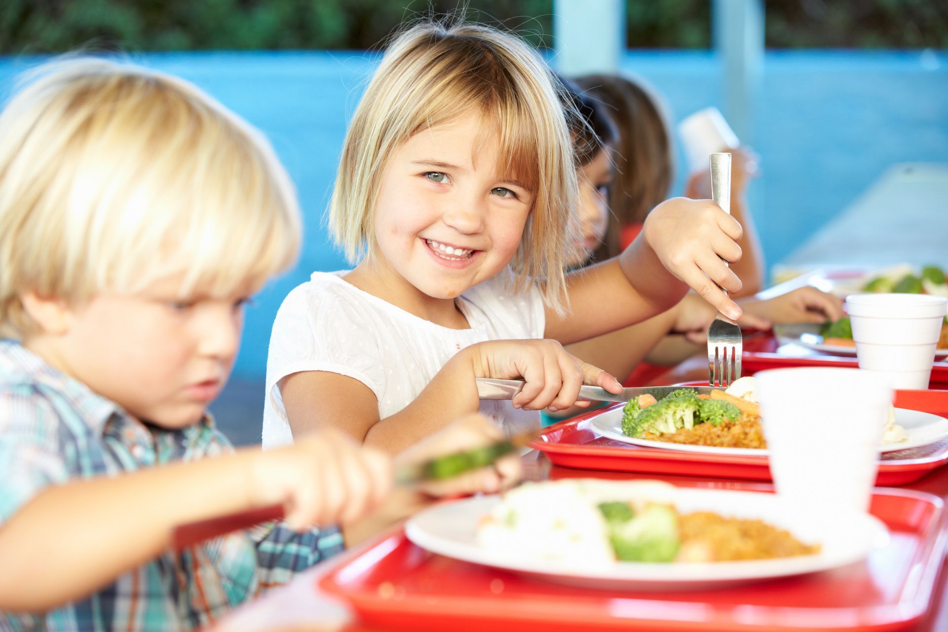 A group of children are sitting at a table eating food.