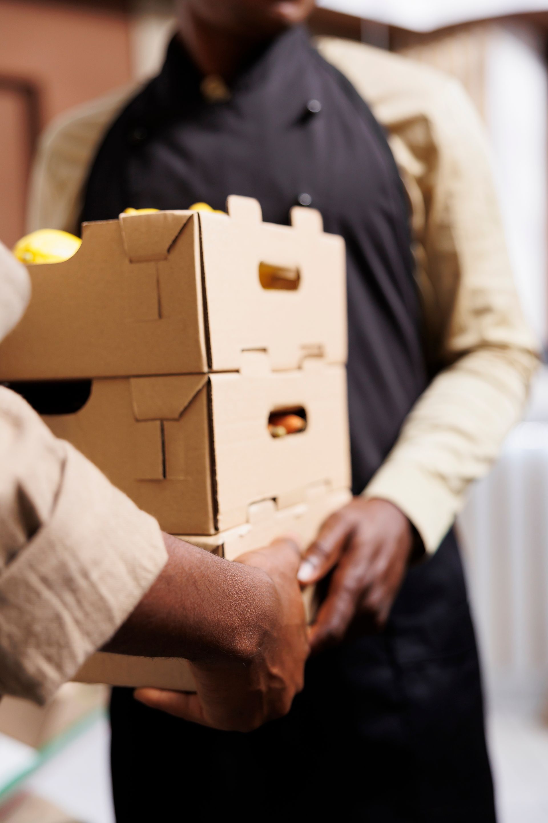 A man in an apron is holding a stack of cardboard boxes