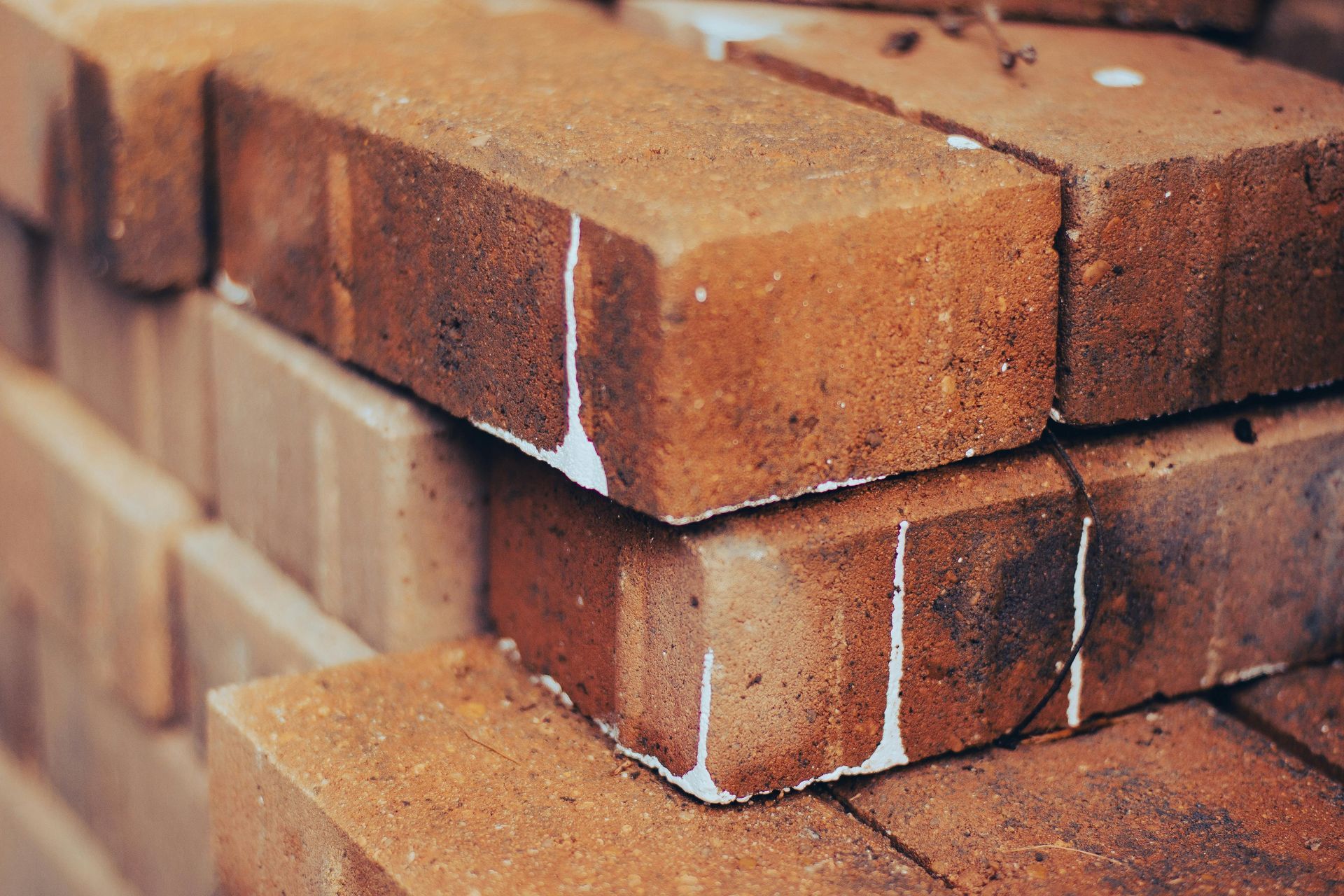Close-up of a stack of weathered, reddish-brown bricks with white residue dripping down their sides.