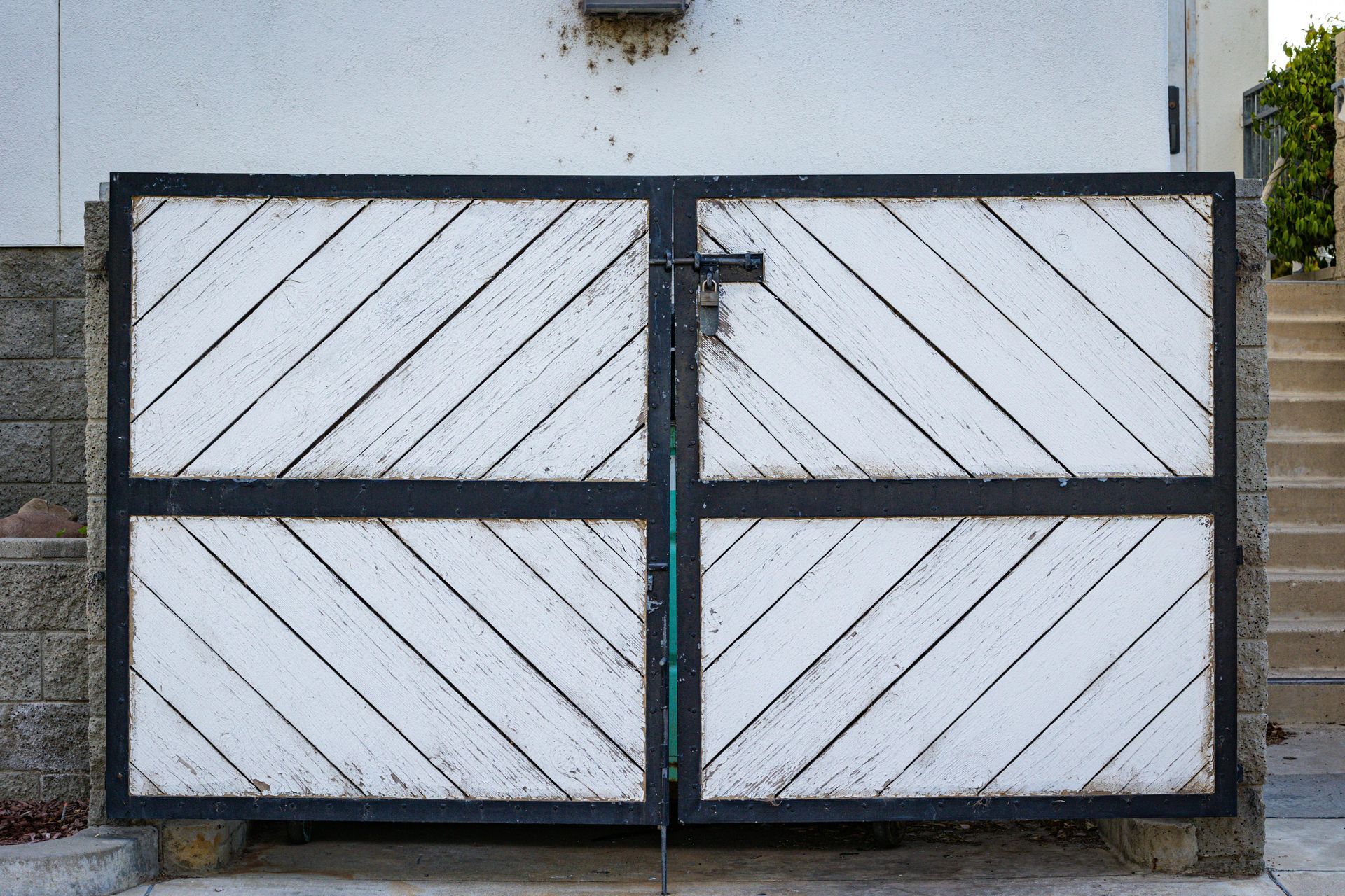 White wooden double gate with black metal frame and diagonal plank design.