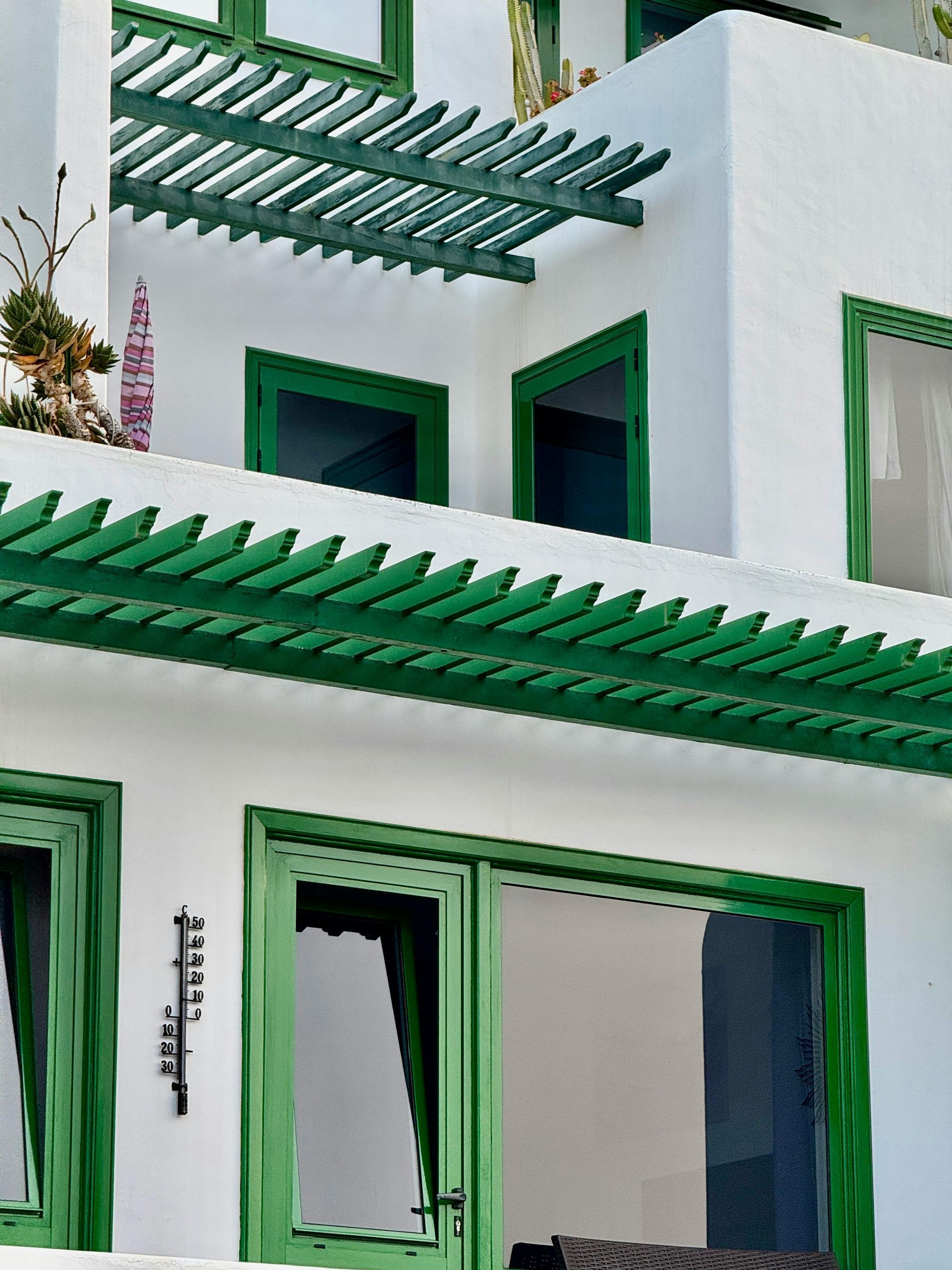 White building with green trim and a pergola.