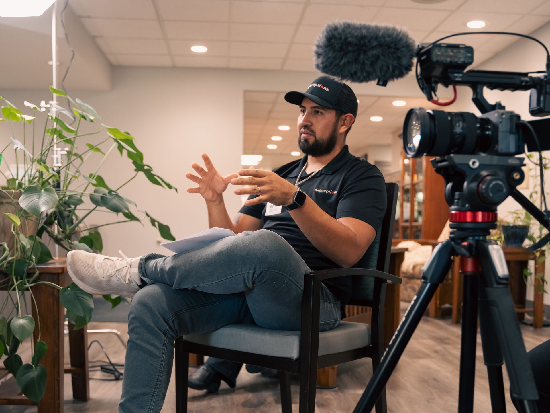 Monico sitting in a chair in front of a camera.