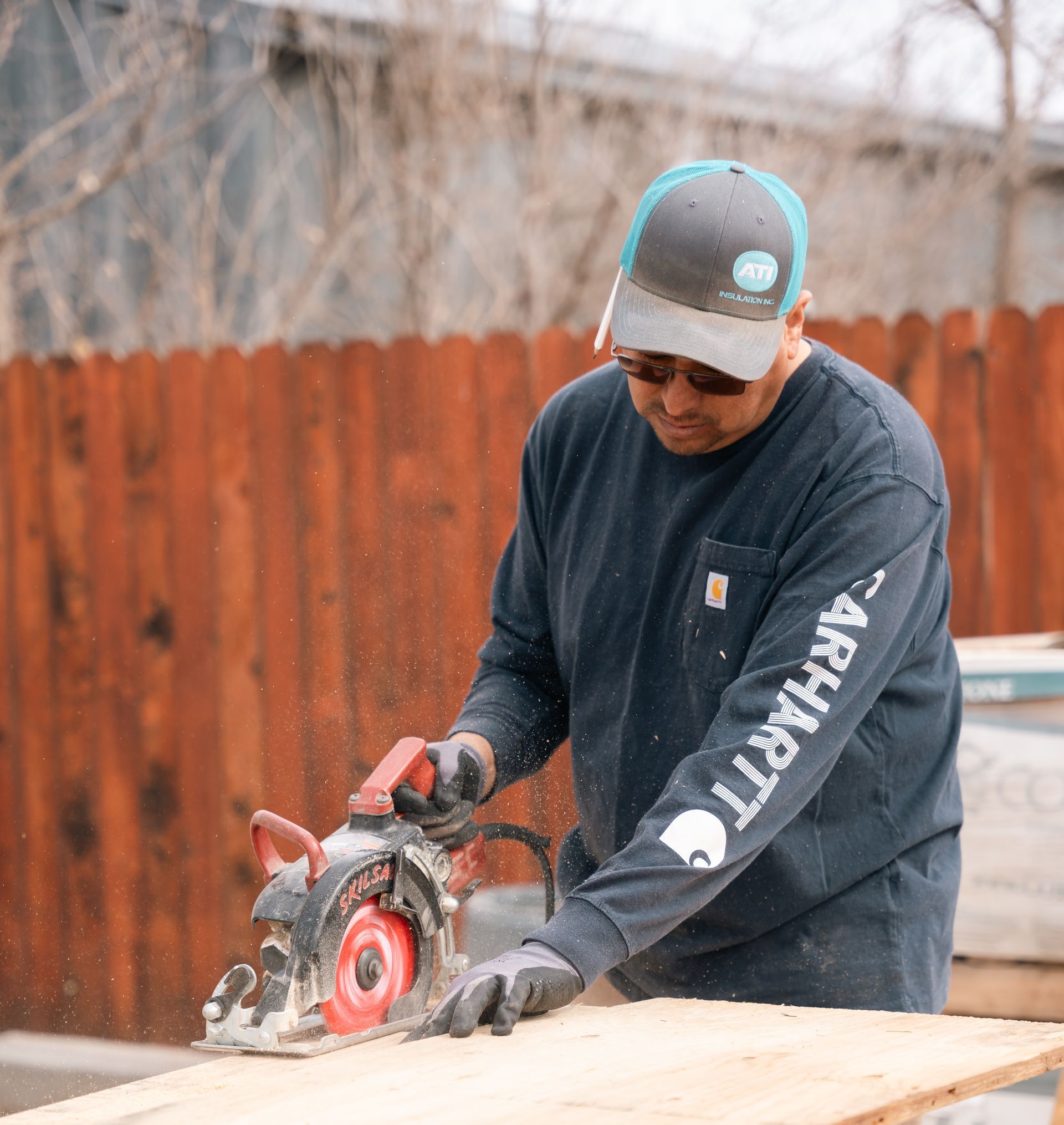 Two men are working on a piece of wood in a workshop.