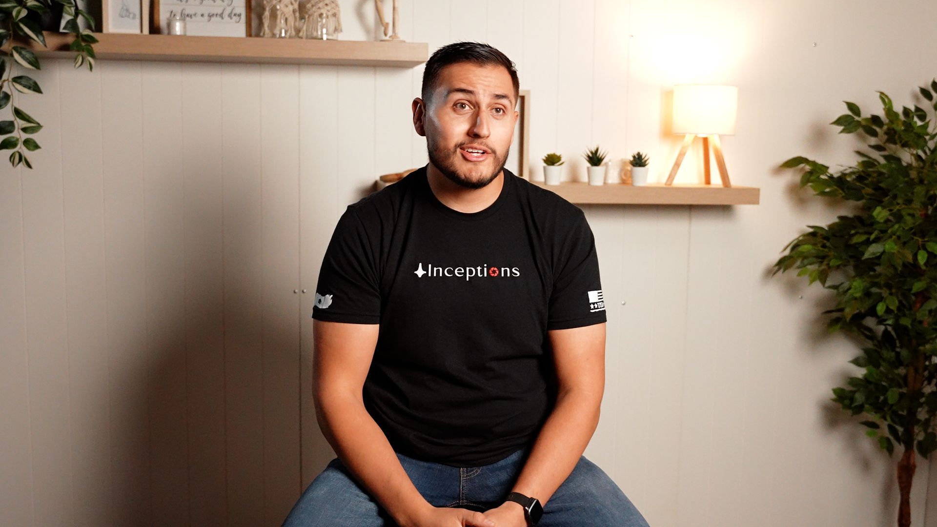 A man wearing a black t-shirt is sitting on a chair.