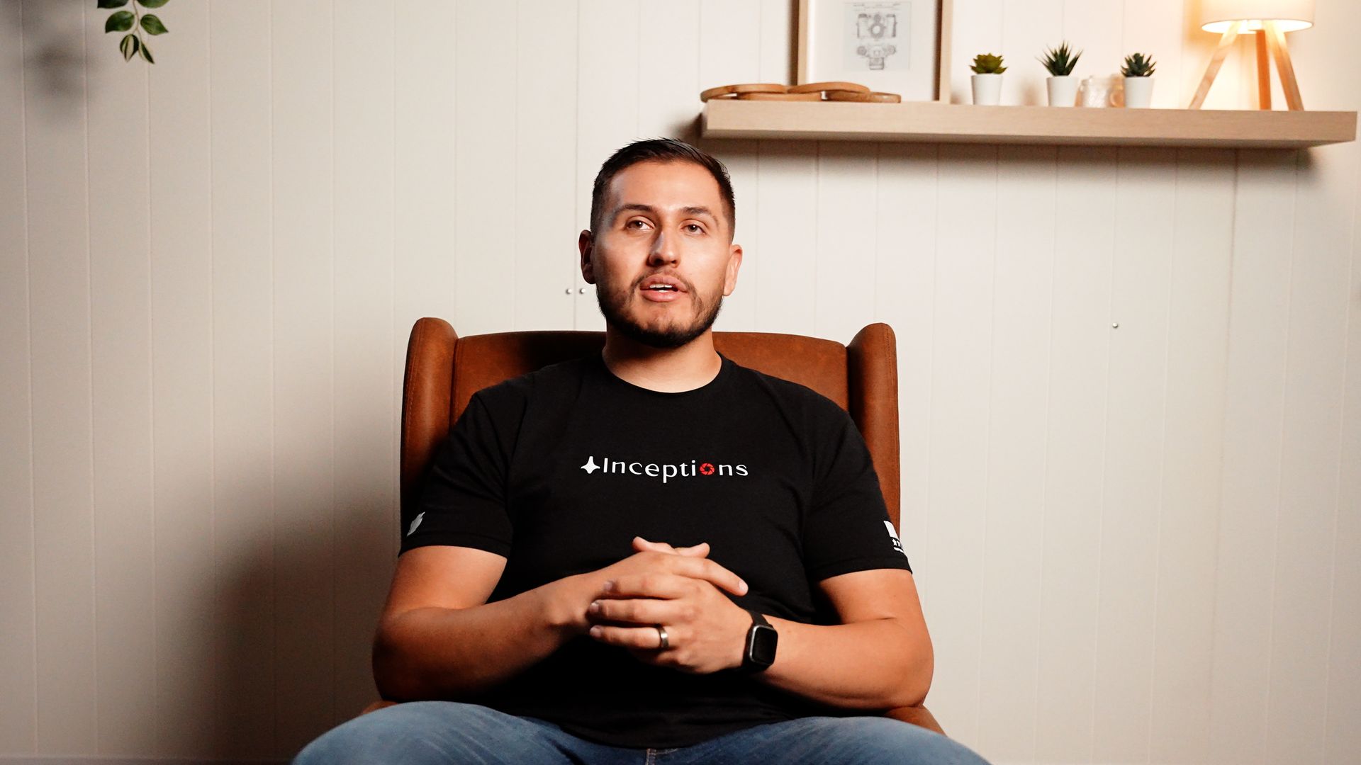 A man is sitting in a chair with his hands folded.