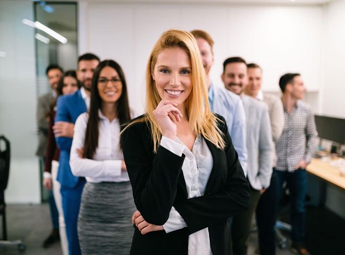 Smiling businesswoman in a black suit with her team in an office setting.