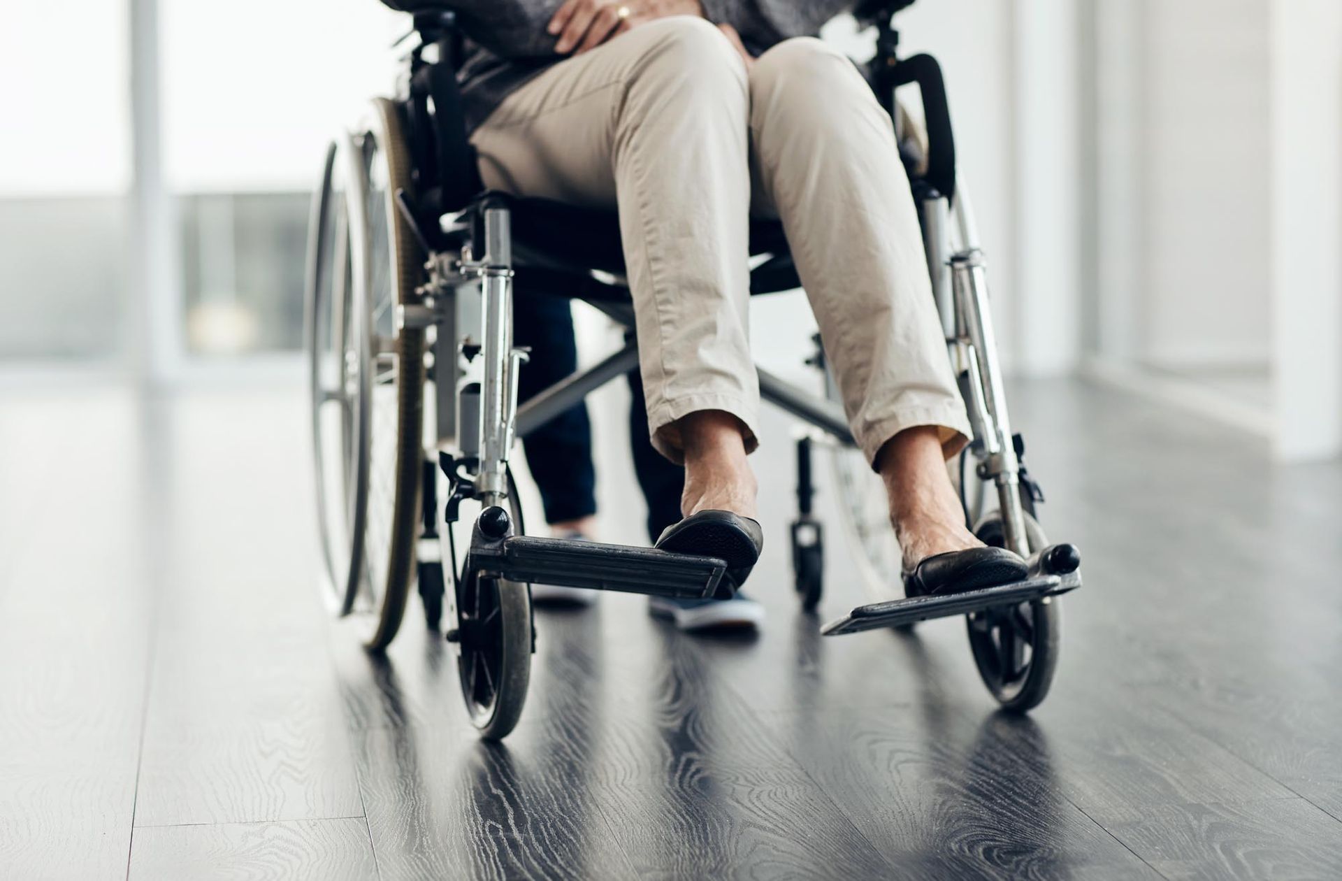 Two people in wheelchairs smiling outdoors, enjoying each other's company.