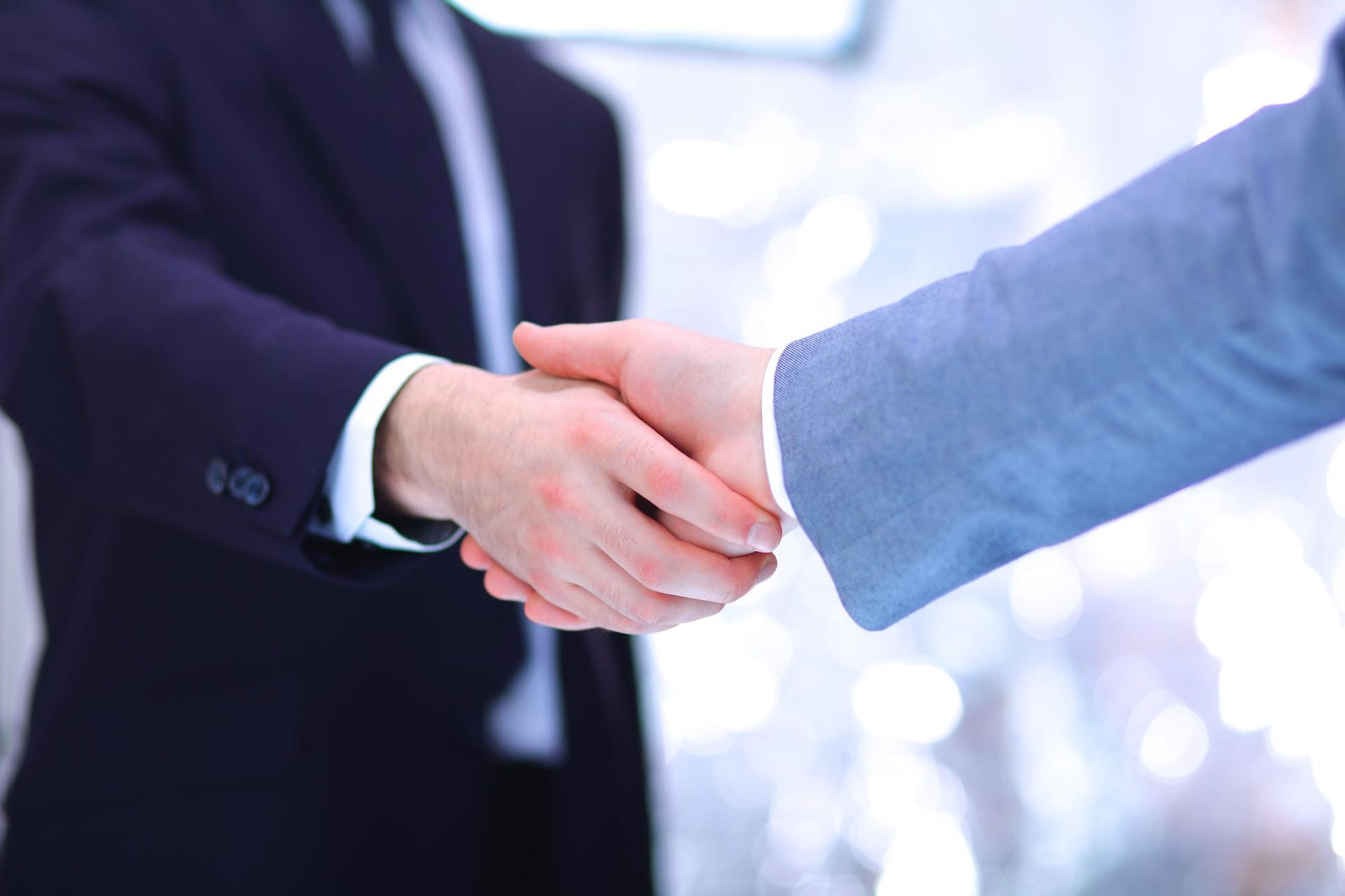 Two business professionals shaking hands, formal setting.