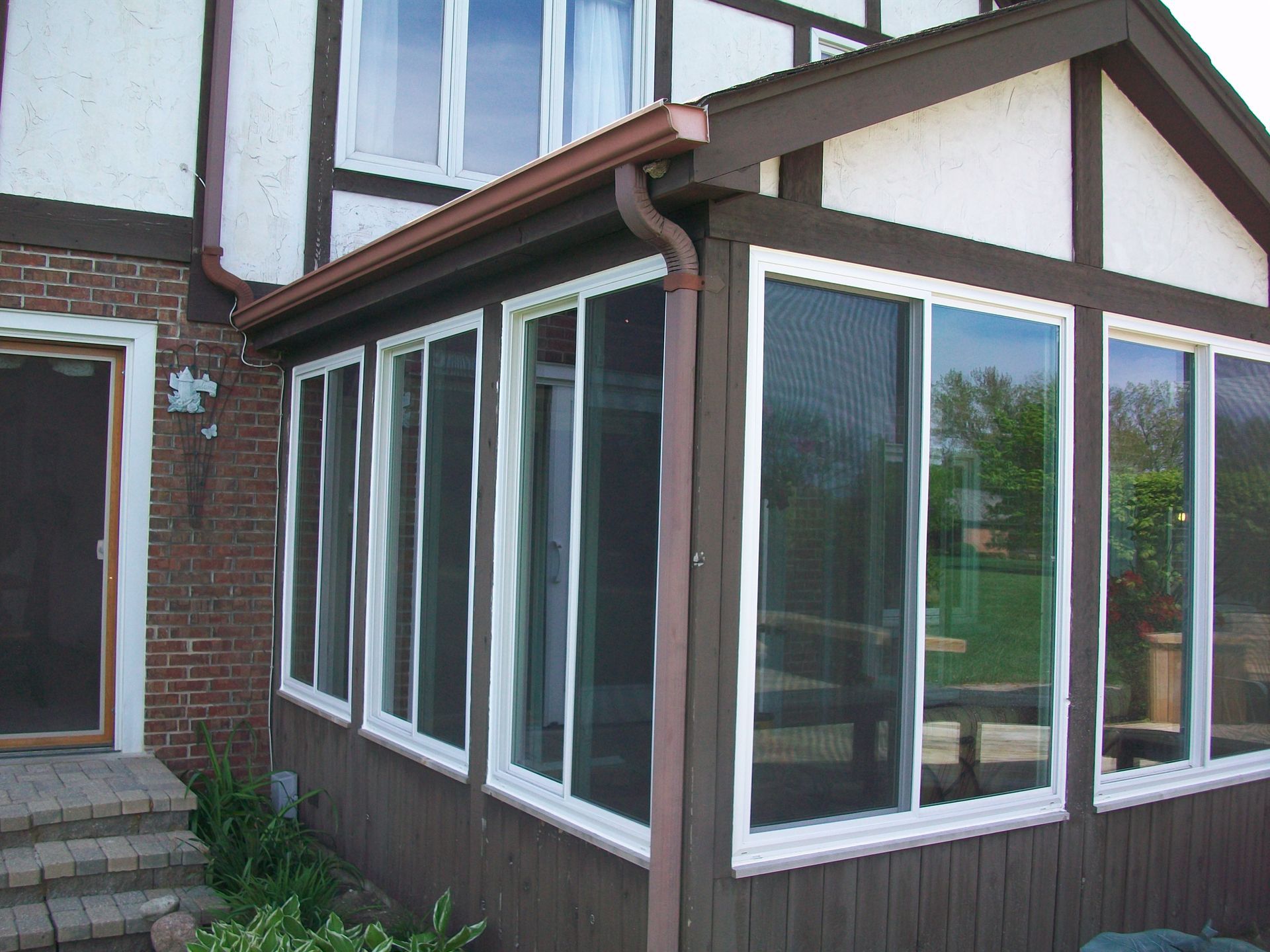 A house with a screened in porch with lots of windows