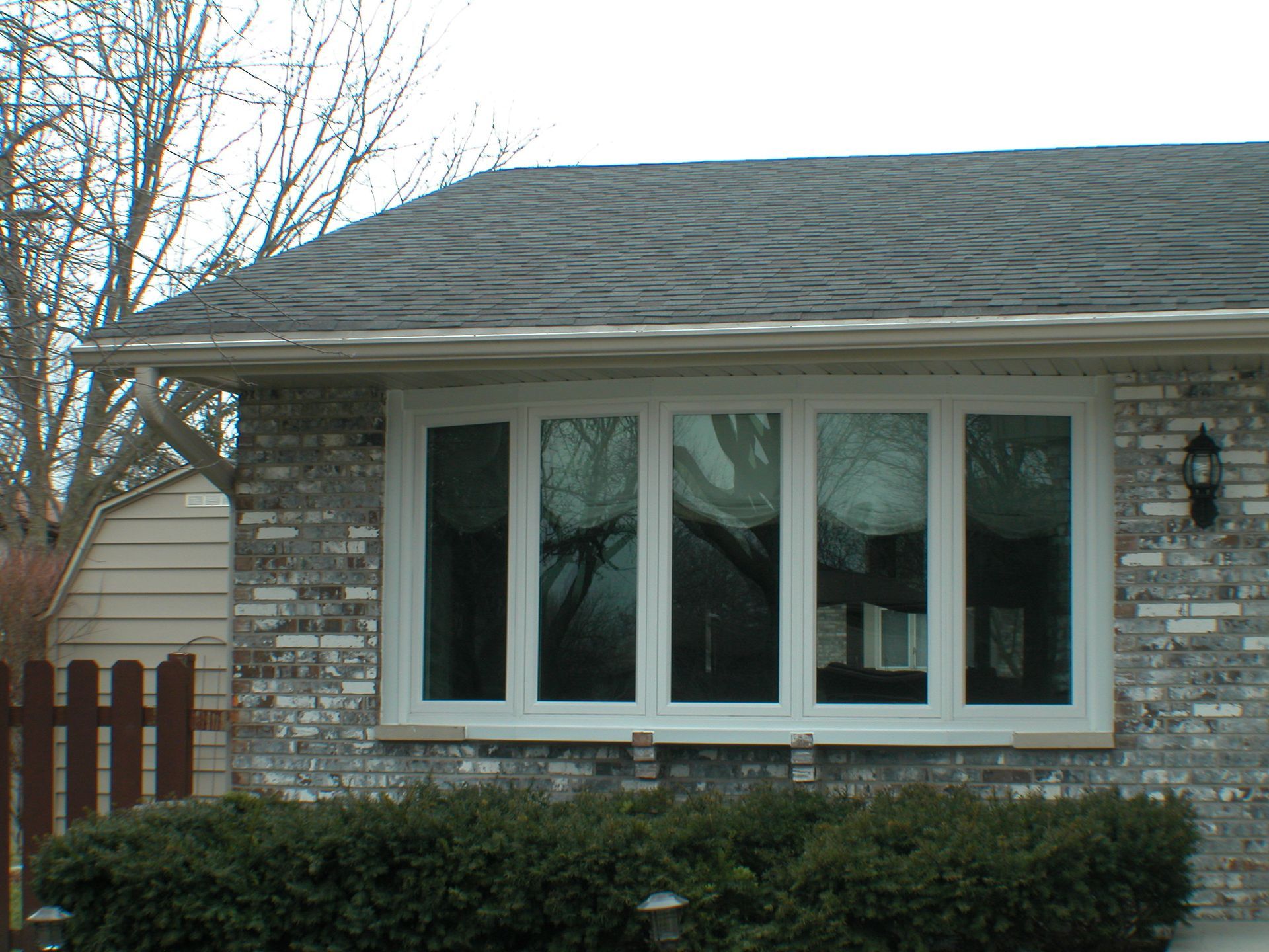 A brick house with white windows and a black roof