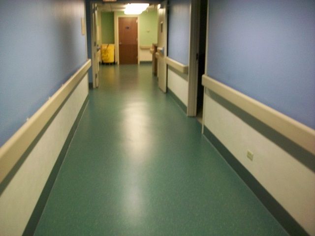 A hospital hallway with green floors and blue walls