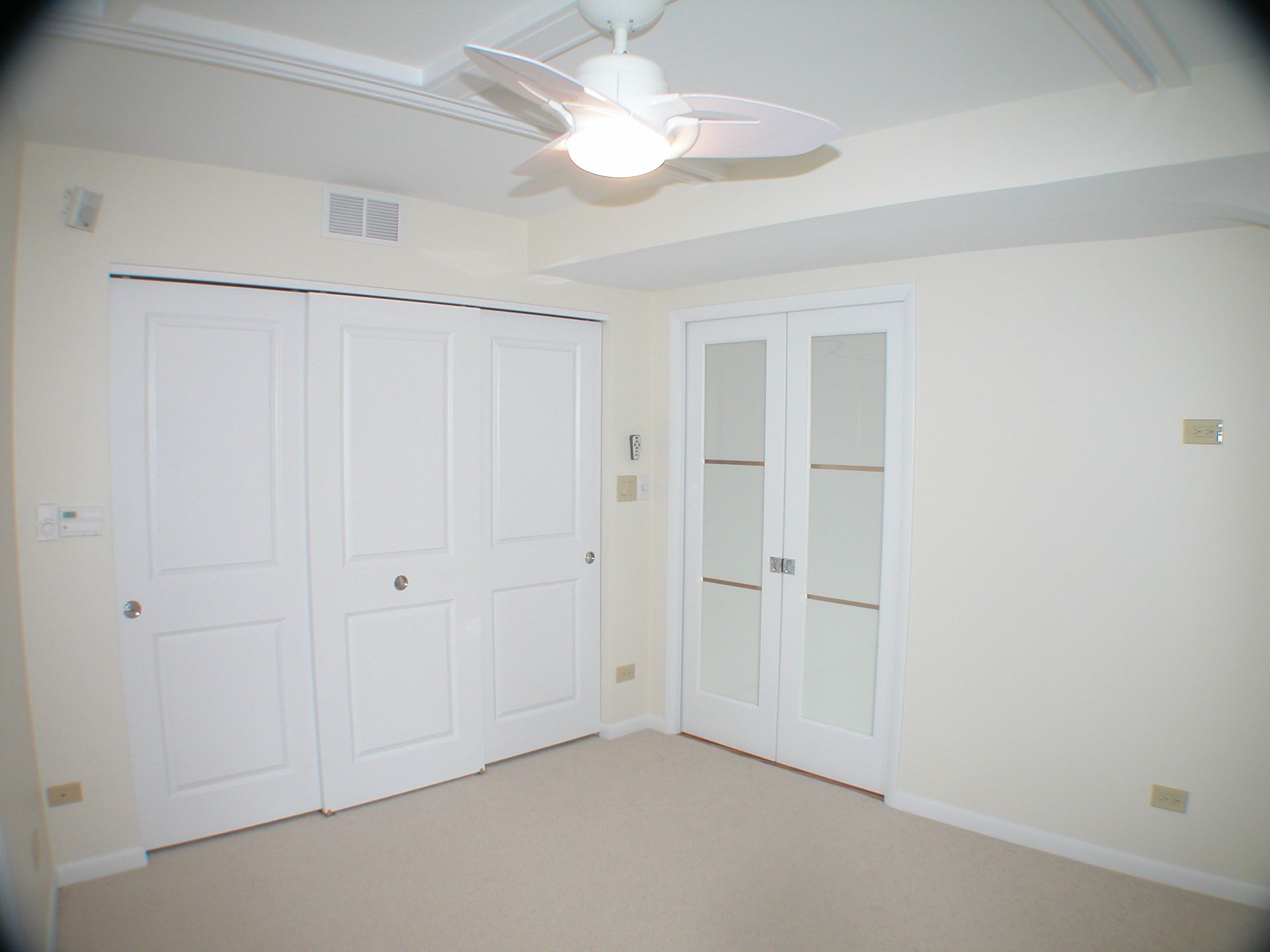 An empty room with a ceiling fan and white doors
