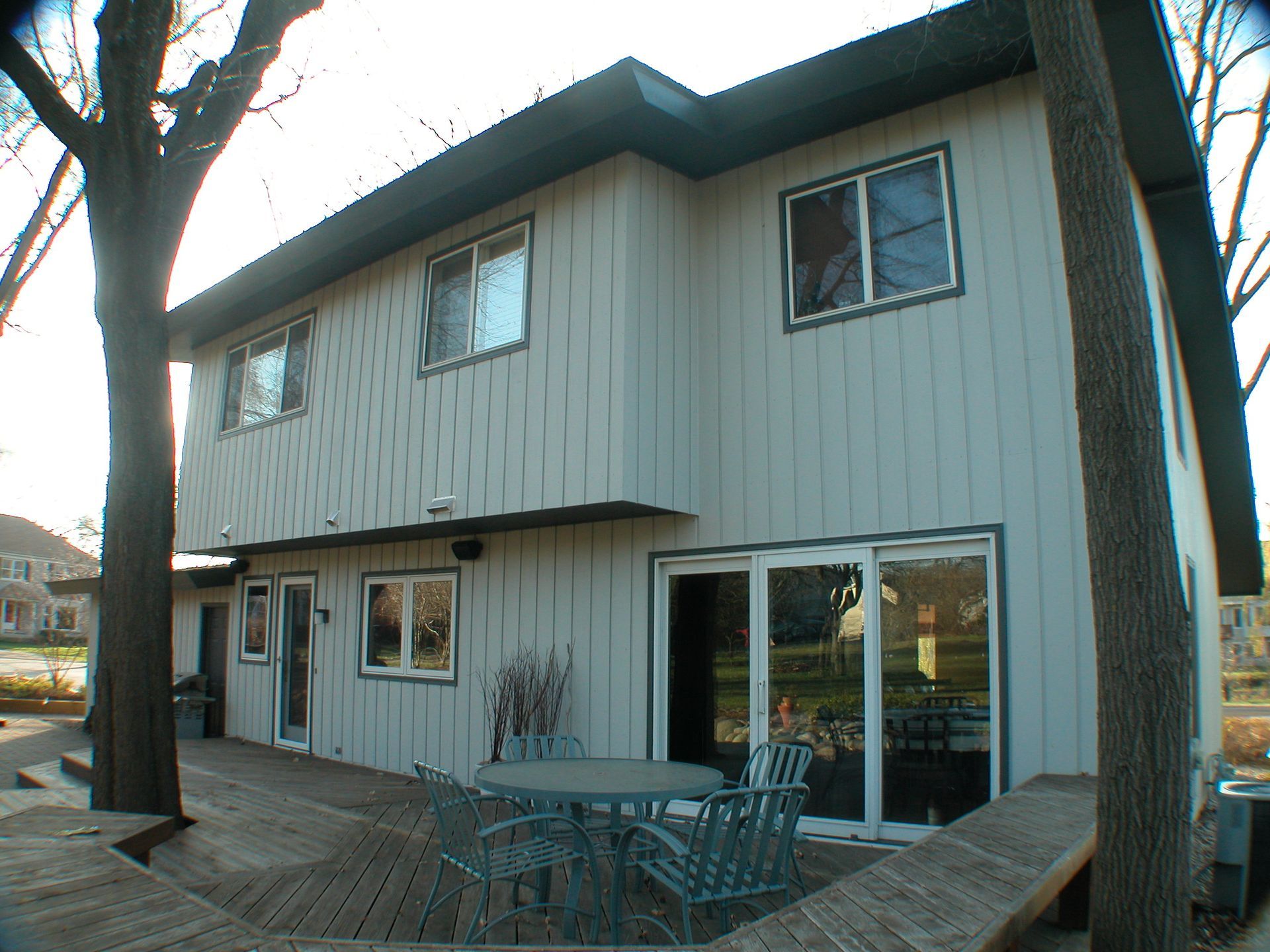 The back of a house with a table and chairs on the deck