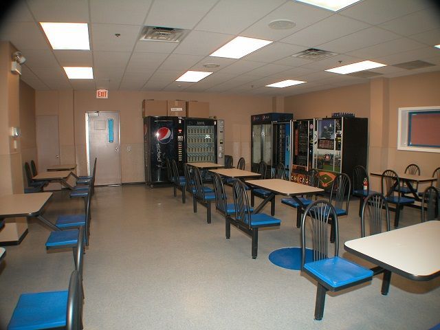 A dining room with tables and chairs and a pepsi vending machine