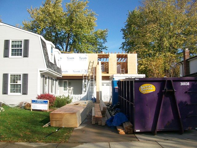 A house under construction with a purple dumpster in front of it
