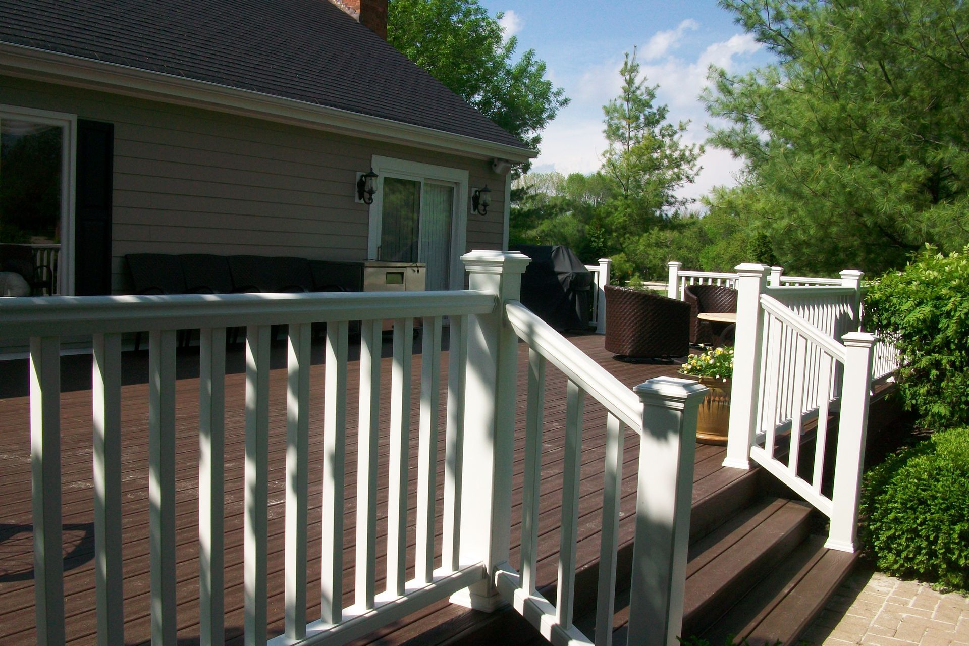 A white railing leading to a deck with a house in the background