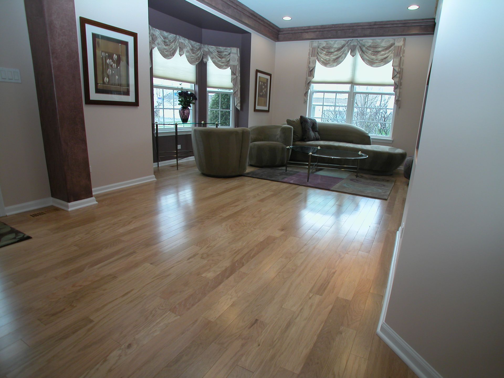 A living room with hardwood floors and a couch and chairs