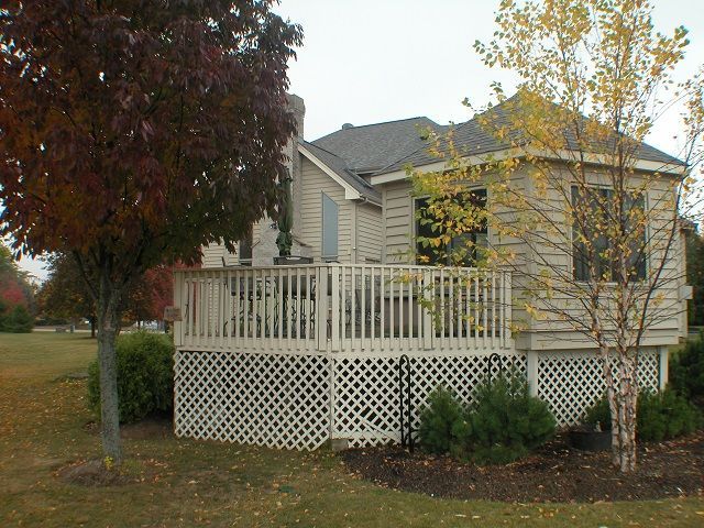 A house with a deck and a tree in front of it