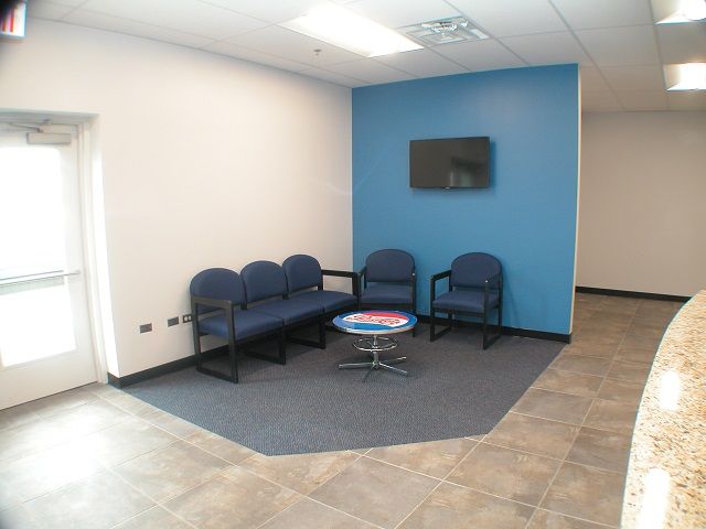 A waiting room with blue chairs and a table