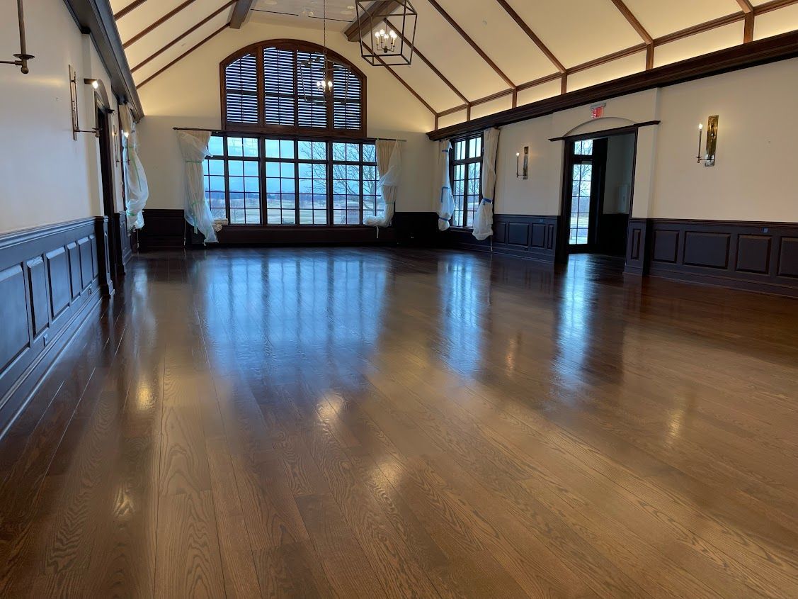 A large empty room with a wooden floor and a stained glass window.