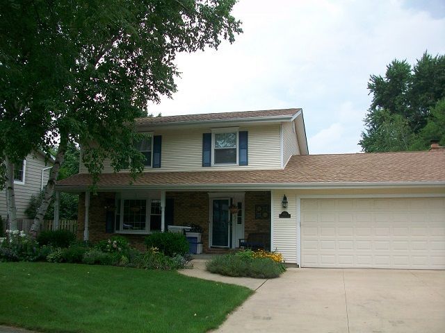 A white house with a brown roof and a white garage door