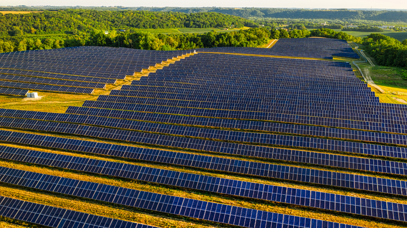 Distesa di pannelli solari in campagna verde, esempio di produzione energetica sostenibile