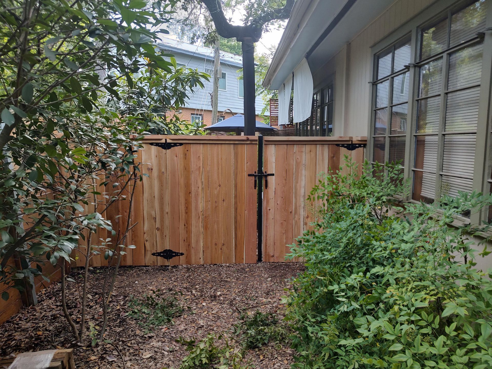 A wooden fence is in the backyard of a house.