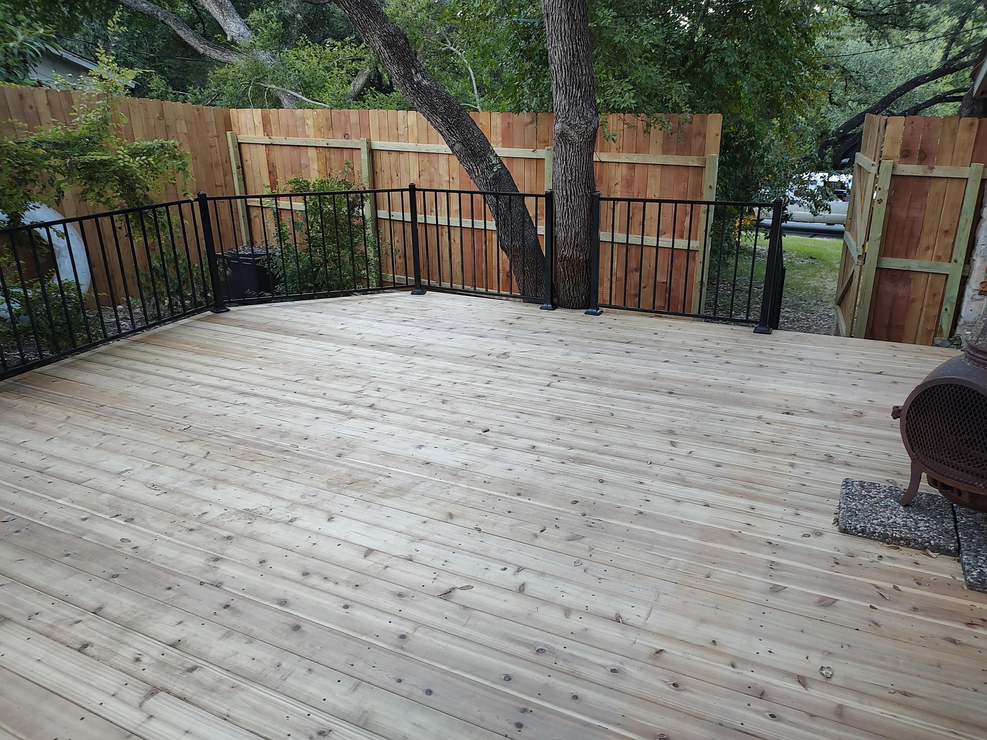 A wooden deck with a fence and trees in the background.
