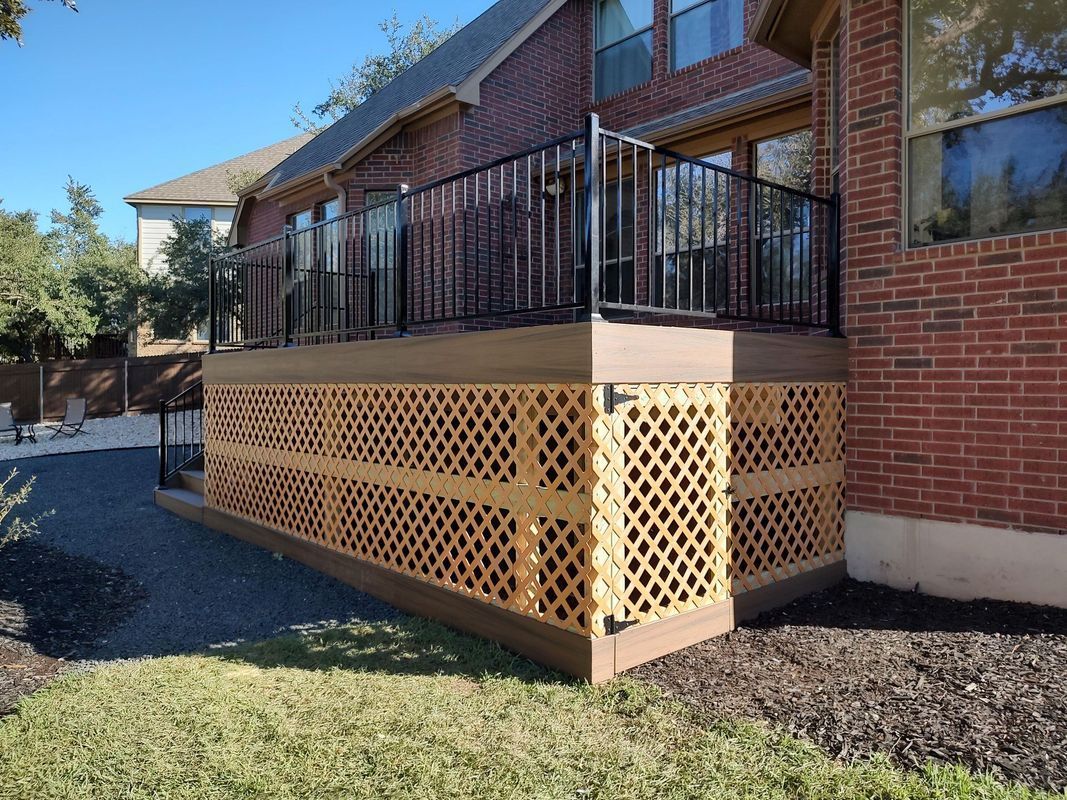 A brick house with a wooden deck and a metal railing.