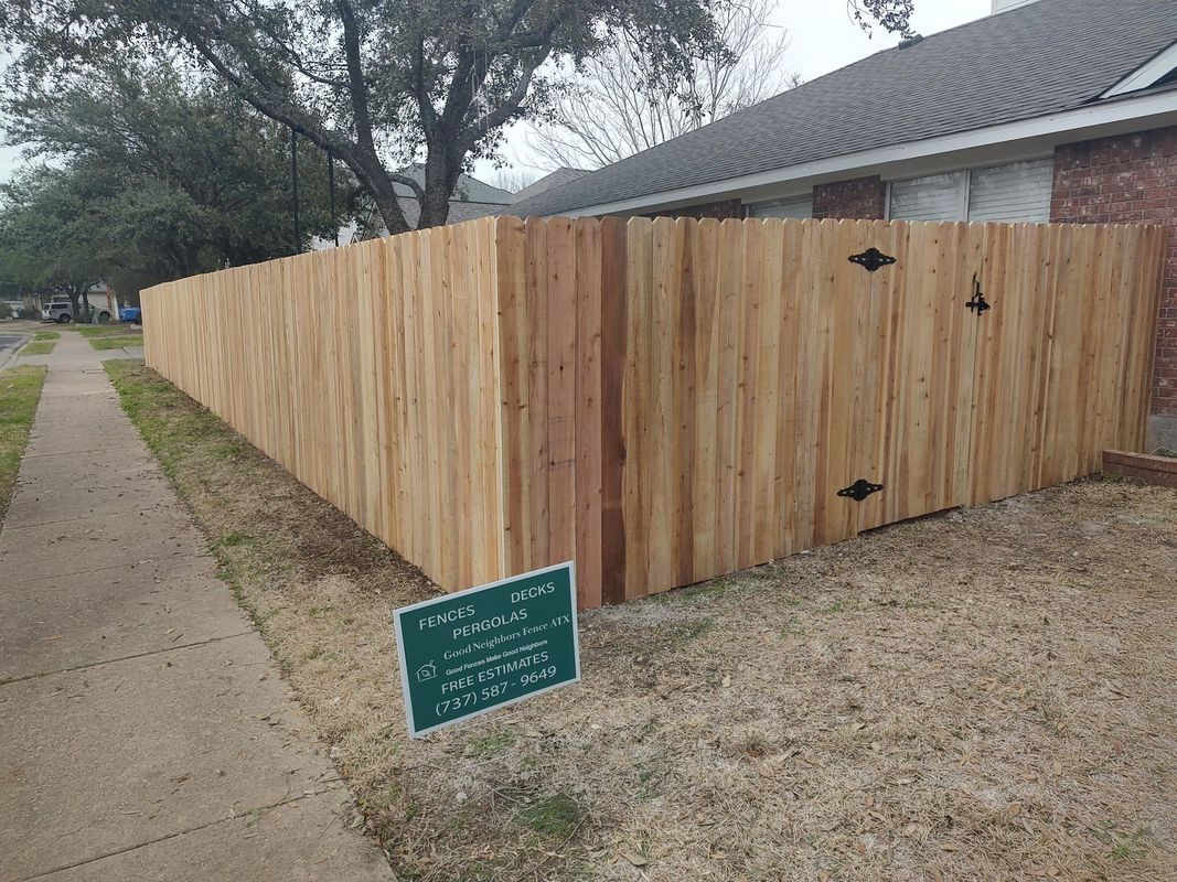 A wooden fence is sitting in front of a brick house.