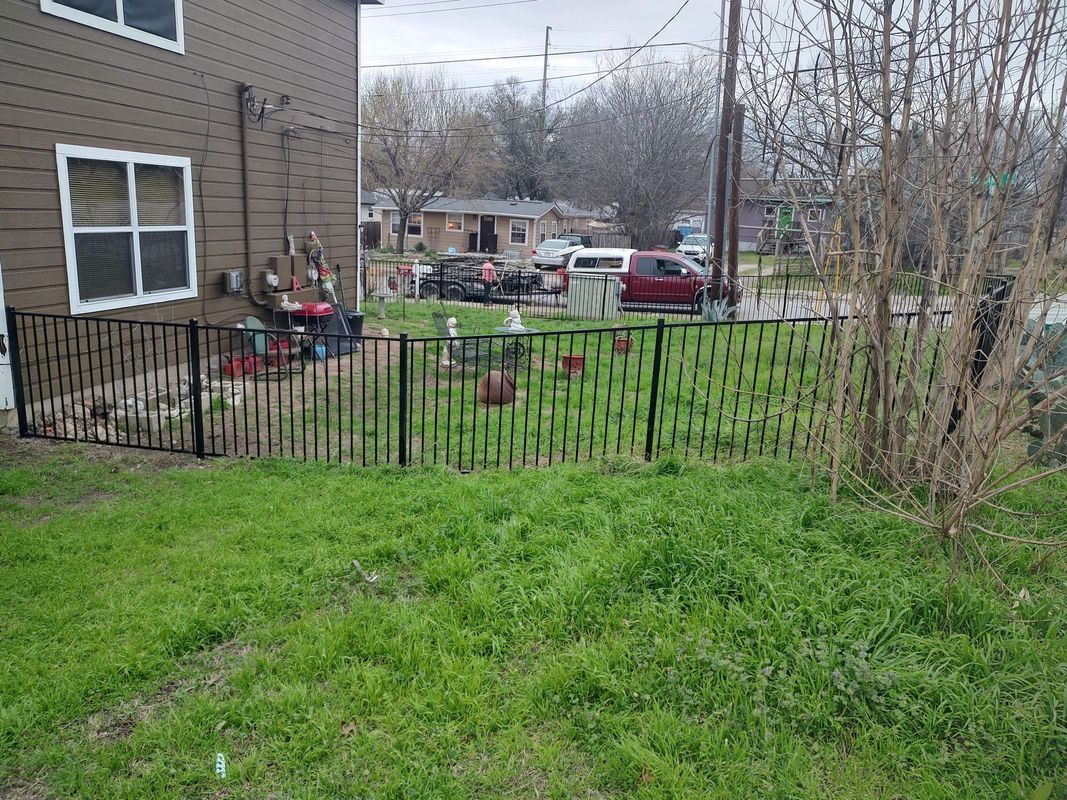 A backyard with a fence and a house in the background.