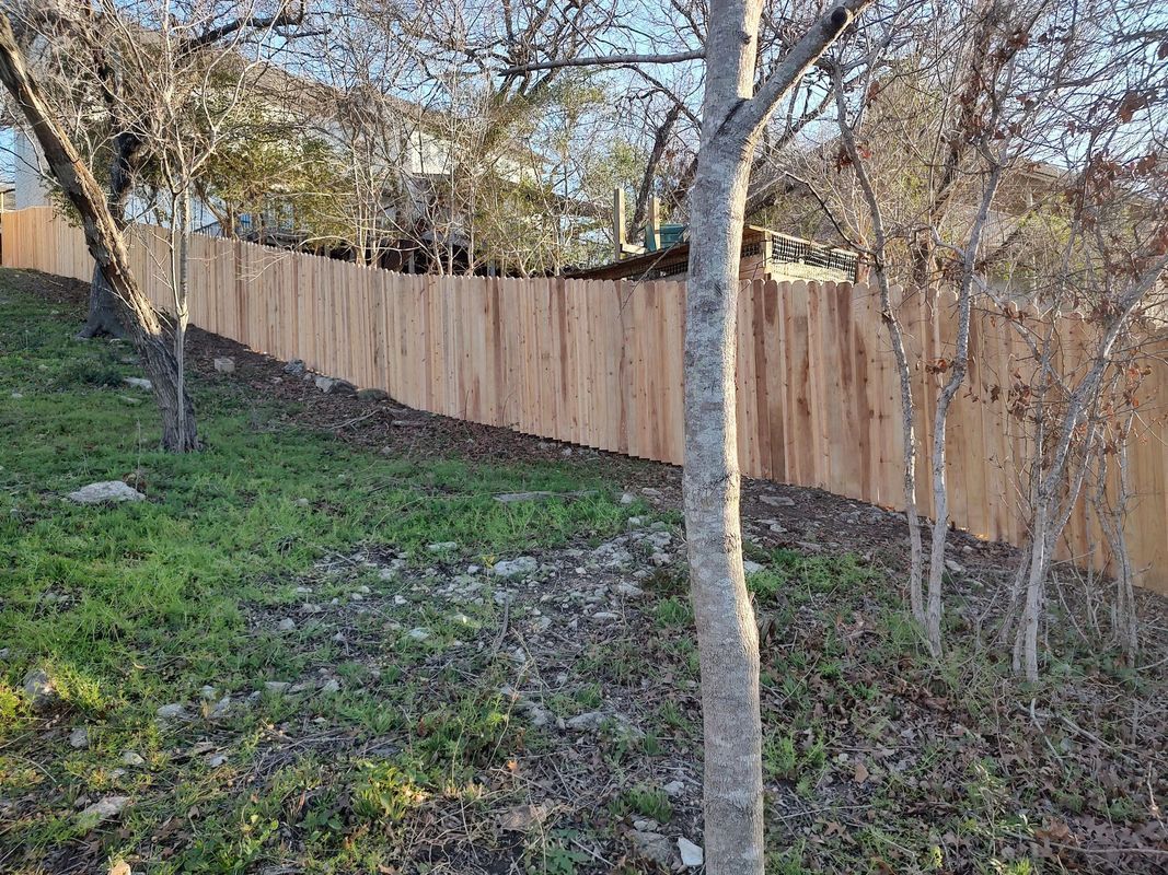 A wooden fence is surrounded by trees in a grassy area.