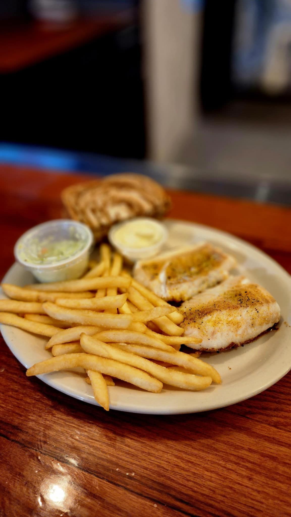 A plate of food with french fries and a sandwich on a wooden table.