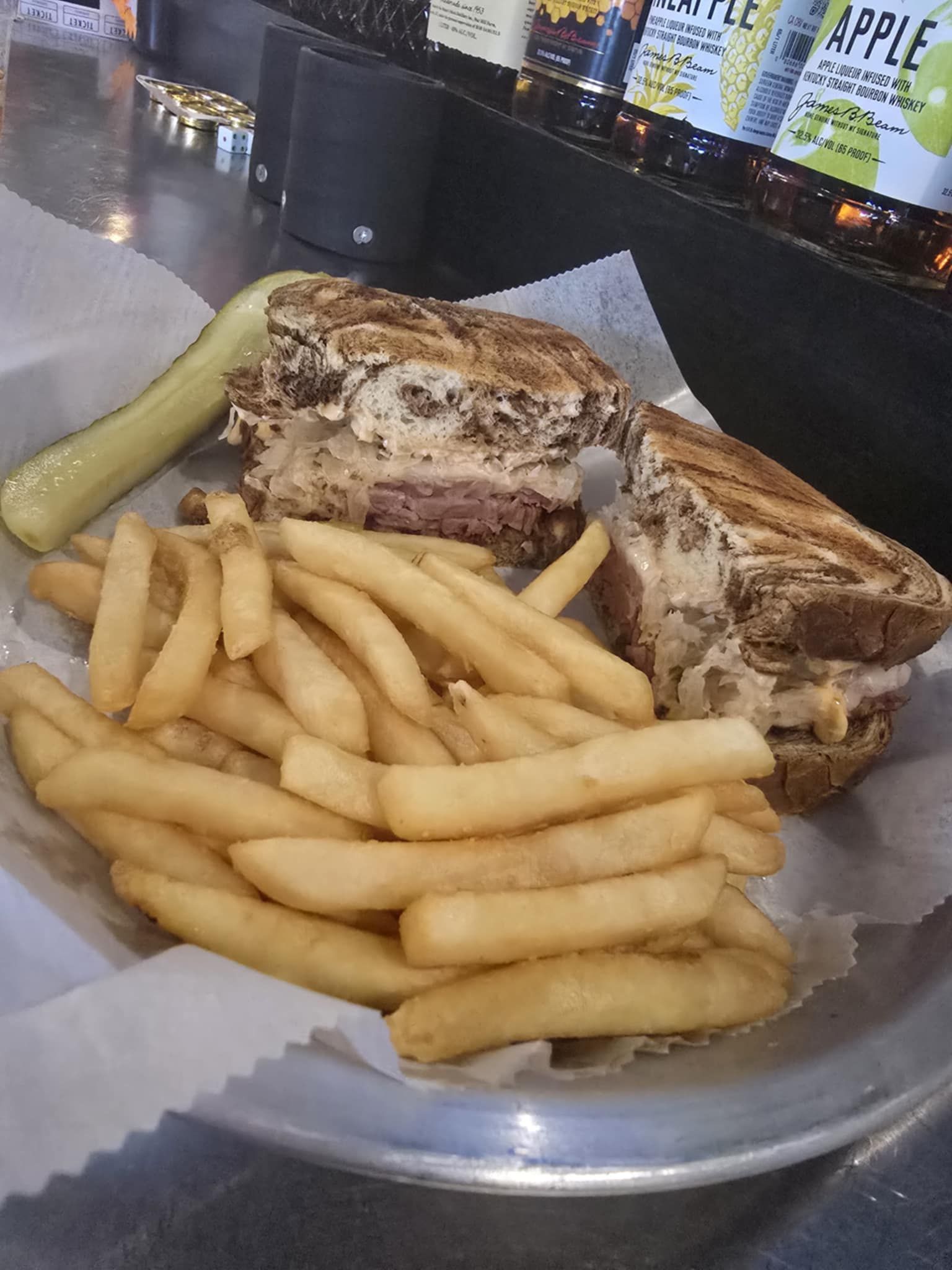 A sandwich with french fries and a pickle on a plate.