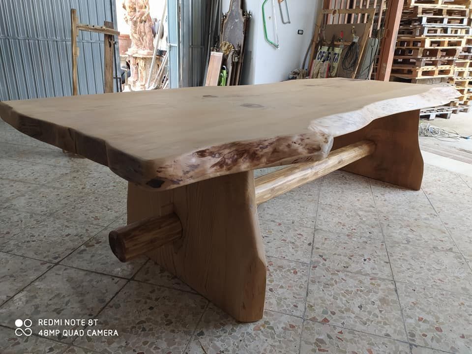 Tavolino da caffè in legno con piano con bordo naturale e design rustico, ambientato in un laboratorio.